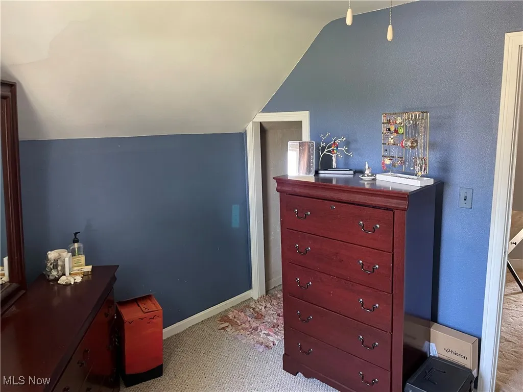 Carpeted bedroom with lofted ceiling and baseboards