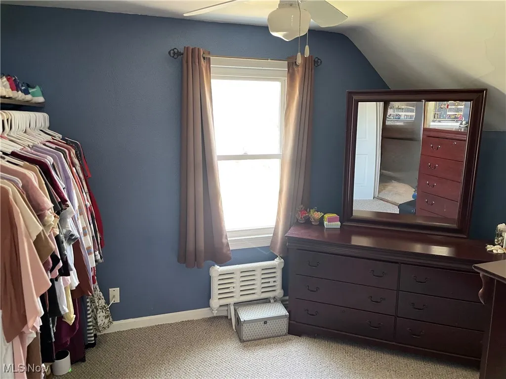 Bedroom with vaulted ceiling, light carpet, and ceiling fan