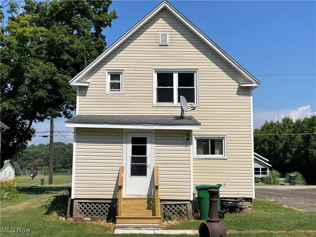 Rear view of property featuring entry steps and a yard