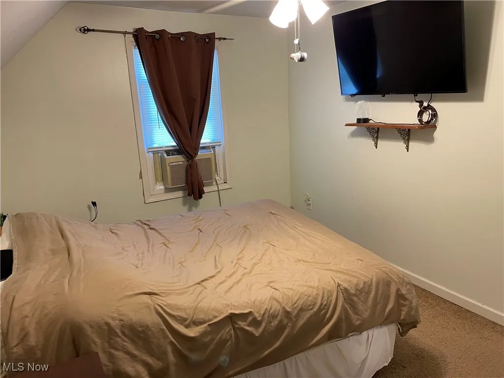 Carpeted bedroom featuring lofted ceiling and baseboards