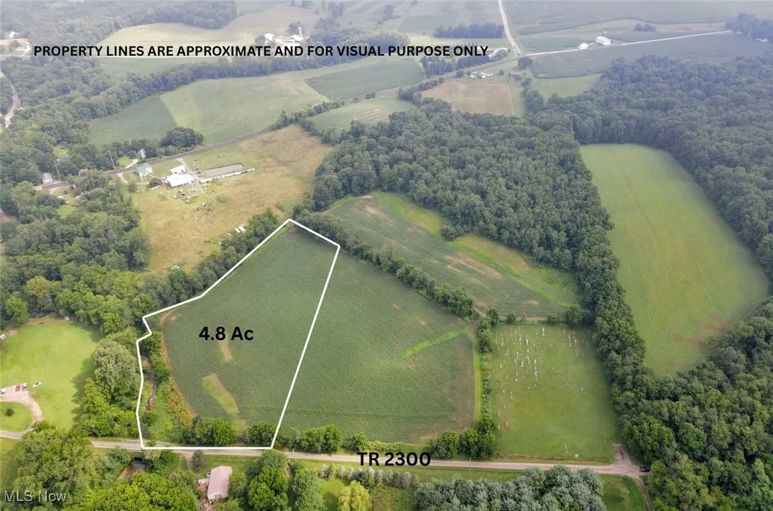 Aerial view of sparsely populated area with property parcel outlined and a forest