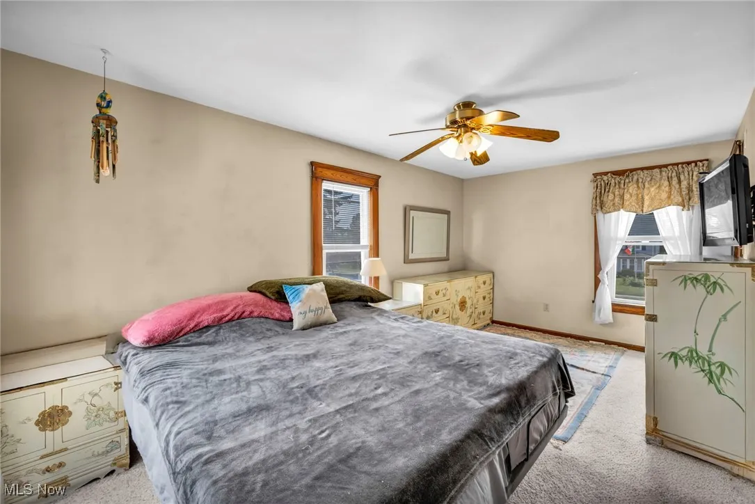 Carpeted bedroom featuring ceiling fan and baseboards