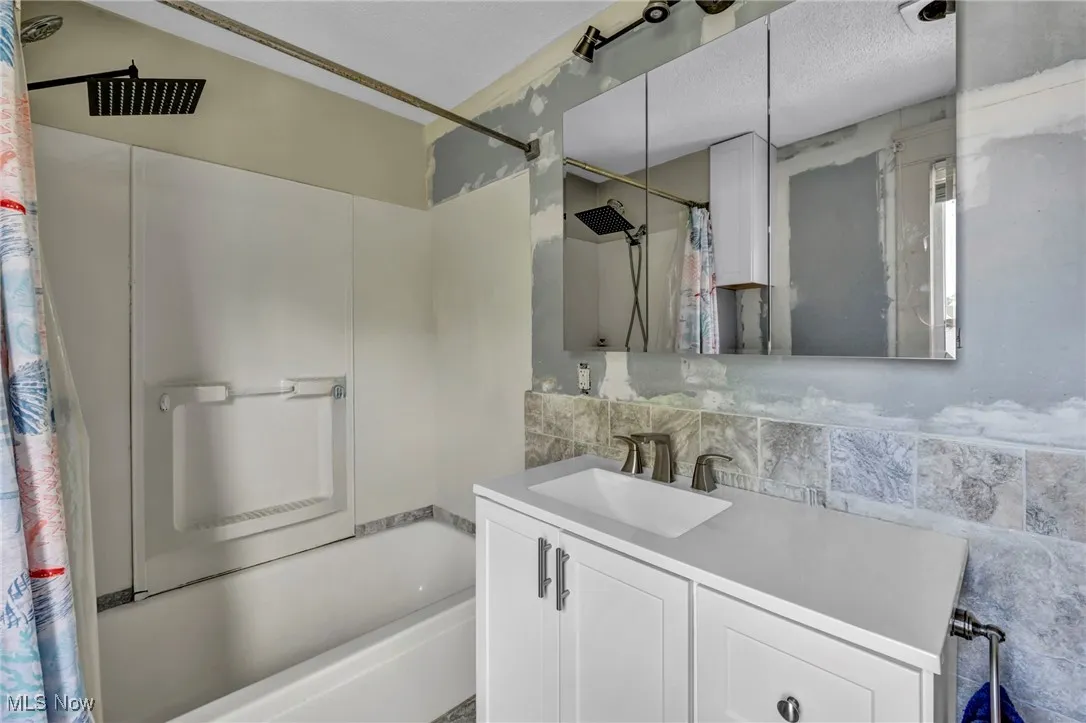 Bathroom featuring shower / bath combination with curtain and vanity
