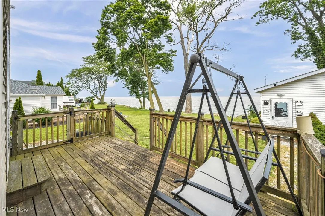 Wooden deck featuring a water view and a lawn