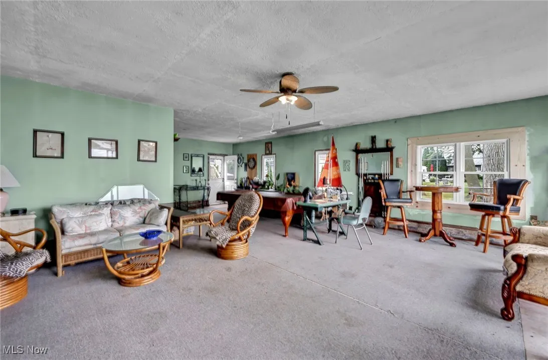 Living room with carpet, a textured ceiling, and ceiling fan