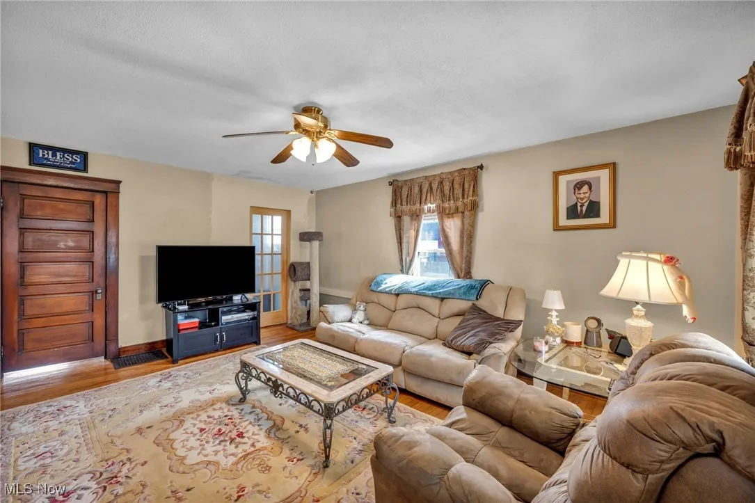 Living room with a ceiling fan, plenty of natural light, and wood finished floors