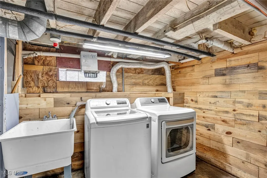 Washroom with wooden walls and washing machine and dryer