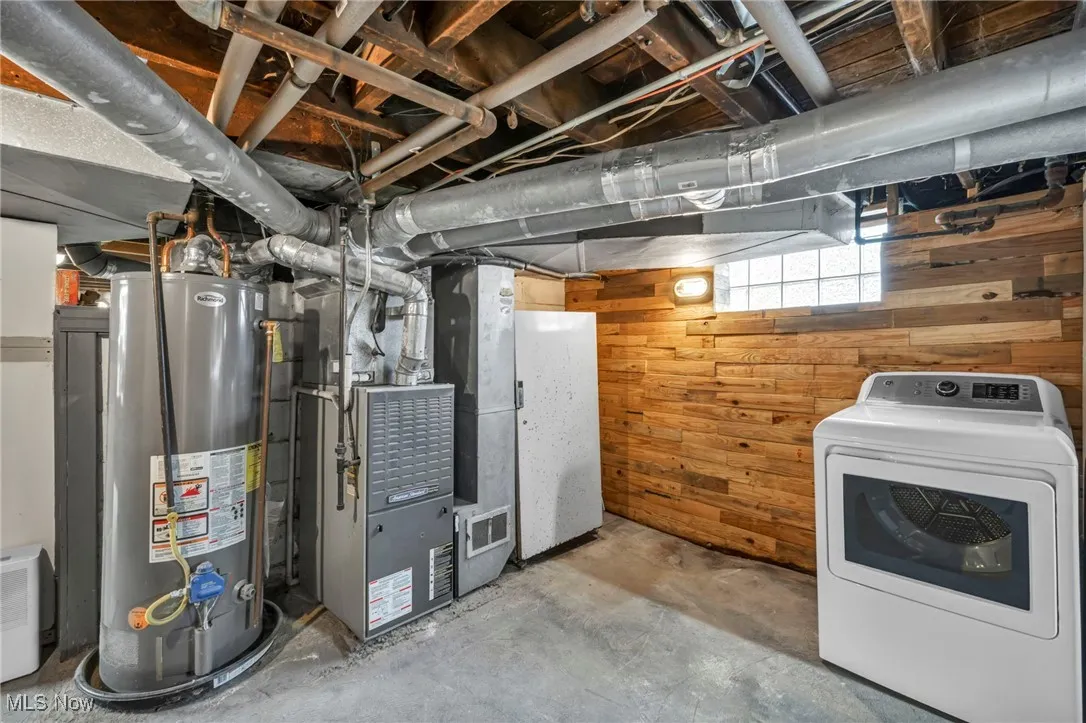 Below grade area featuring washer / clothes dryer, gas water heater, wooden walls, and heating unit