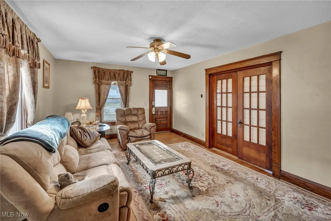Living room featuring ceiling fan, french doors, wood finished floors, and a textured ceiling