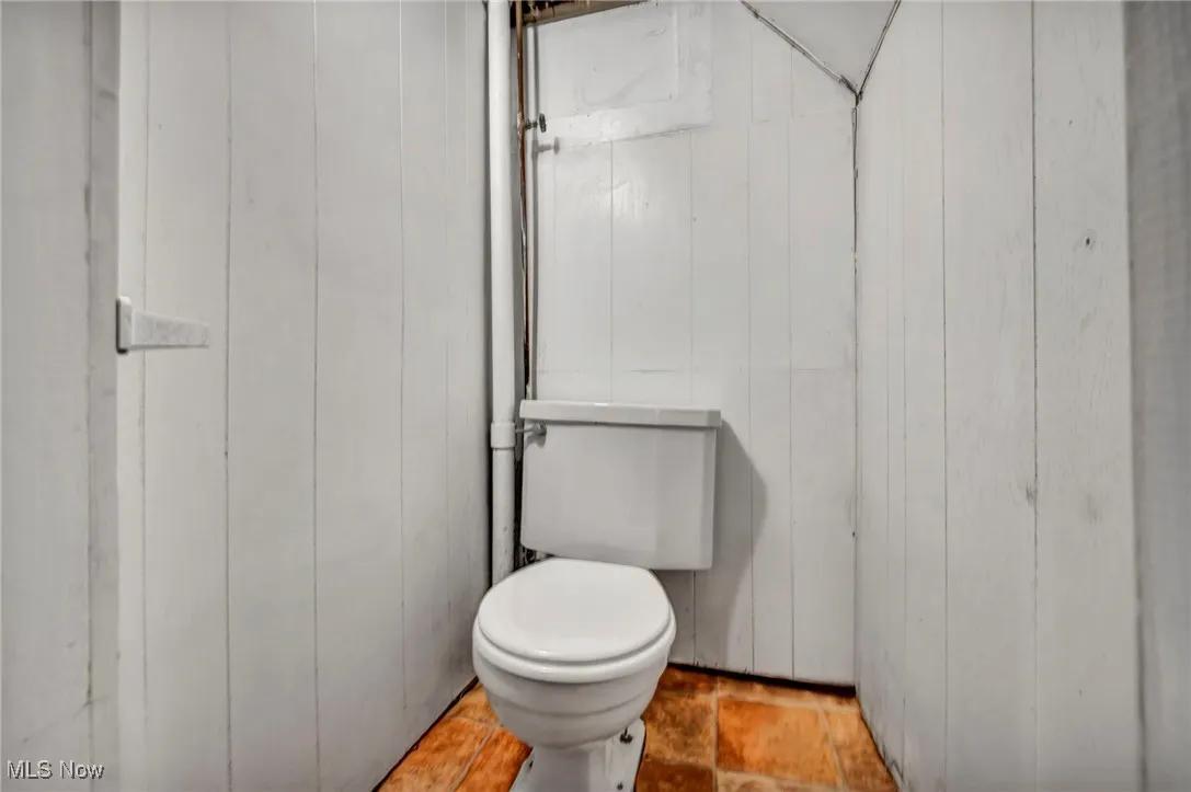 Bathroom featuring toilet and wood walls