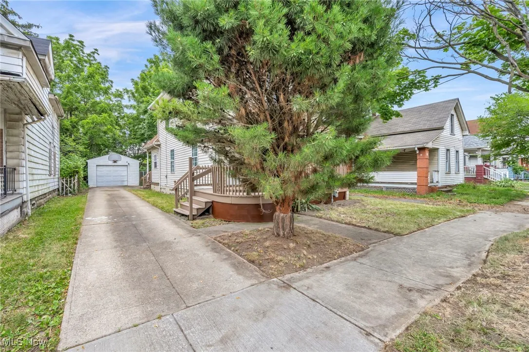 View of front facade featuring concrete driveway, a garage, an outbuilding, and a wooden deck