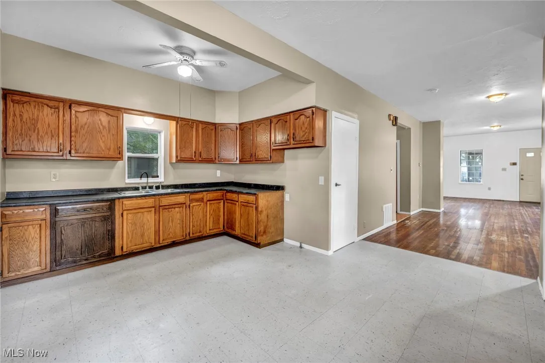 Kitchen featuring brown cabinets, dark countertops, a ceiling fan, and paneled dishwasher