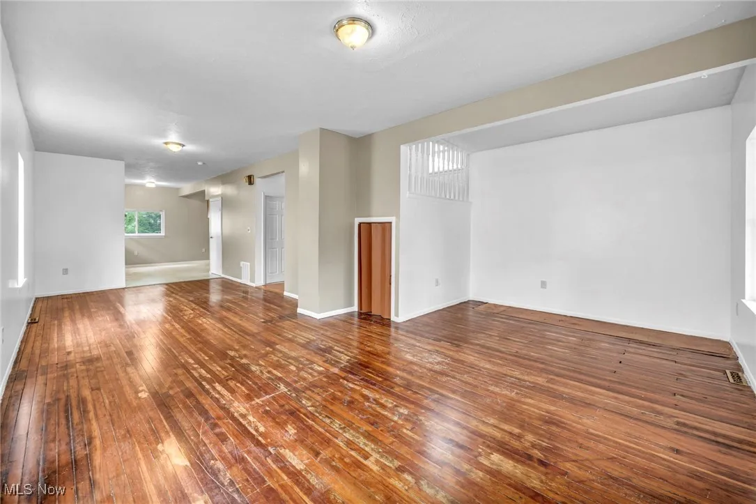Unfurnished living room featuring hardwood / wood-style flooring and baseboards