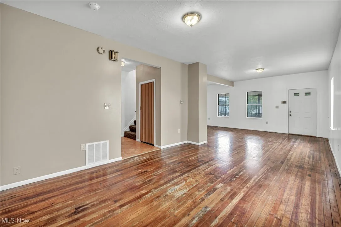 Unfurnished living room featuring stairs and wood-type flooring