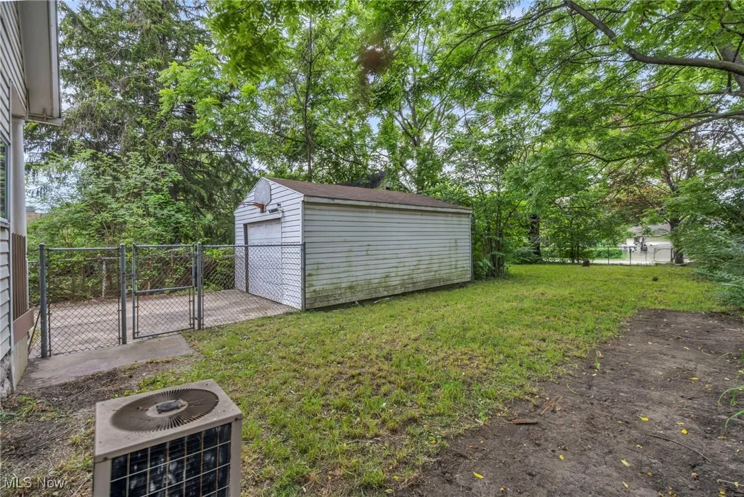 View of yard featuring a gate, an outbuilding, and a fire pit