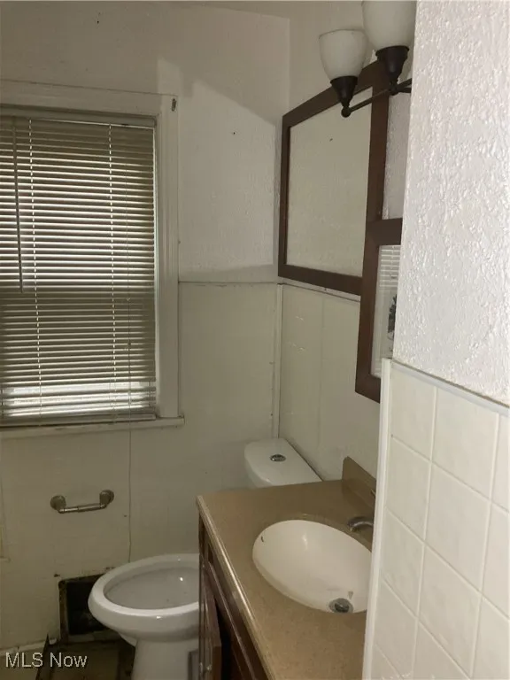 Half bathroom featuring tile walls and vanity