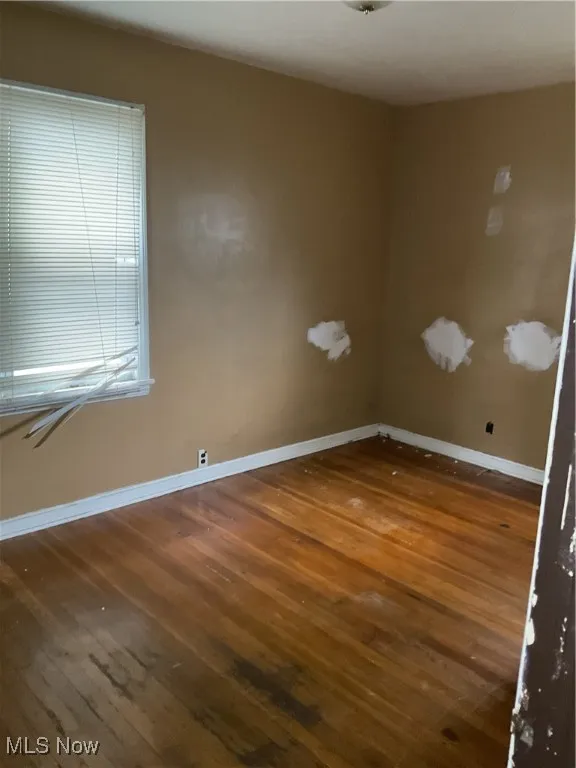 Spare room featuring dark wood-style flooring