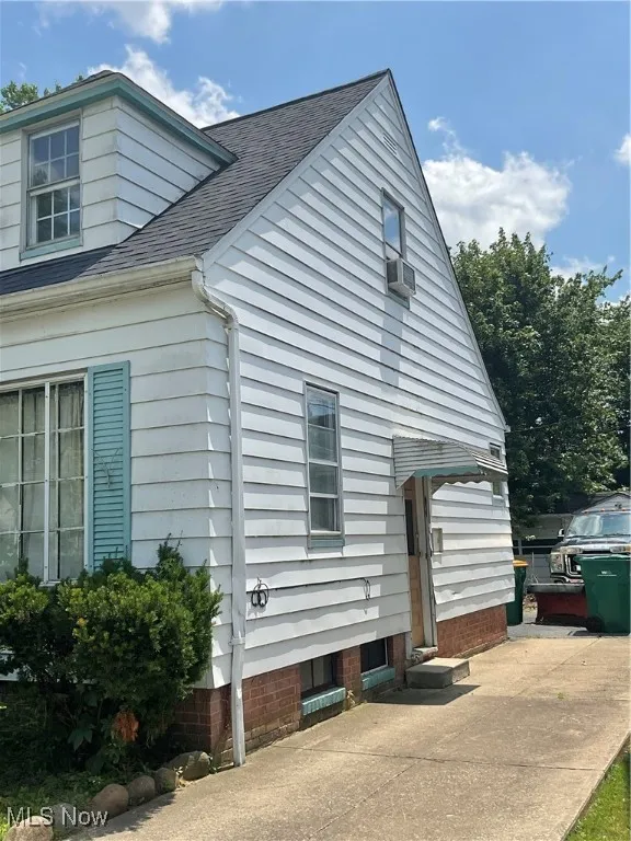 View of side of property with roof with shingles