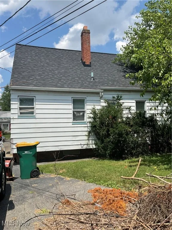 Back of house featuring a shingled roof and a chimney