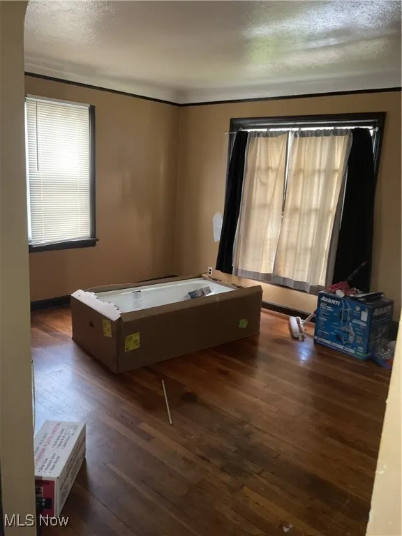 Bedroom featuring multiple windows, hardwood / wood-style floors, and a textured ceiling