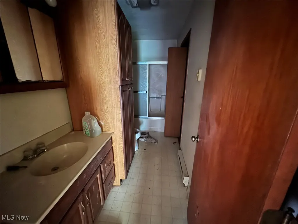 Bathroom featuring vanity and shower / bath combination with glass door