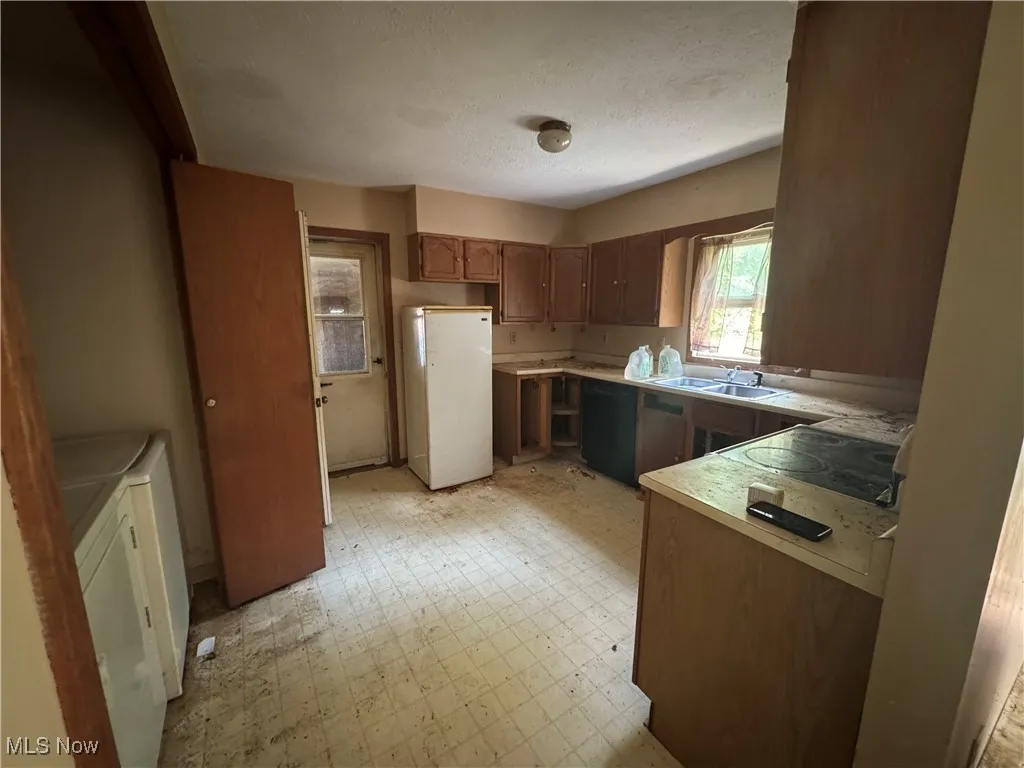 Kitchen with freestanding refrigerator, light floors, light countertops, electric cooktop, and black dishwasher