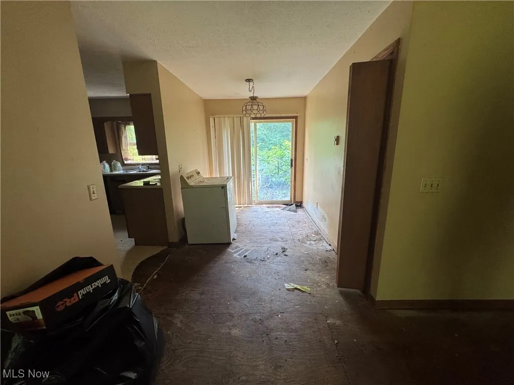 Hallway with plenty of natural light, washer / dryer, a textured ceiling, and a chandelier