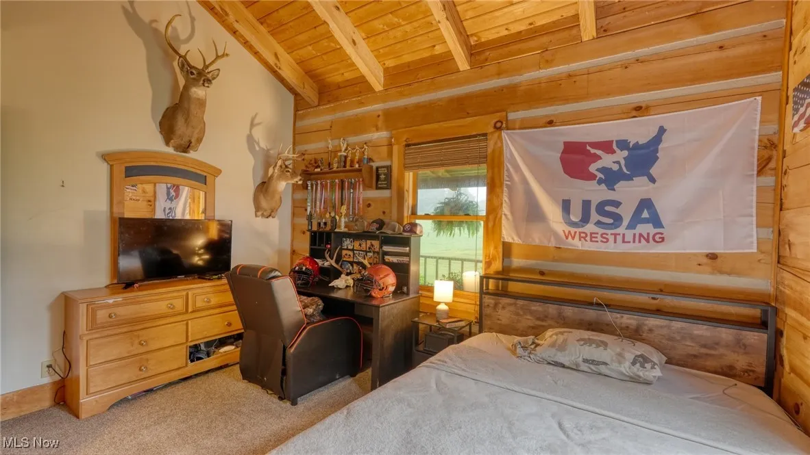 Bedroom featuring wood ceiling, carpet floors, and wood walls