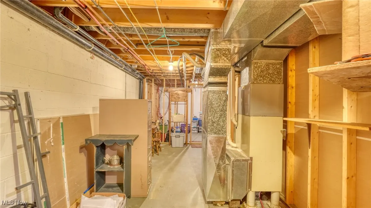 Unfinished below grade area with heating unit and concrete block wall