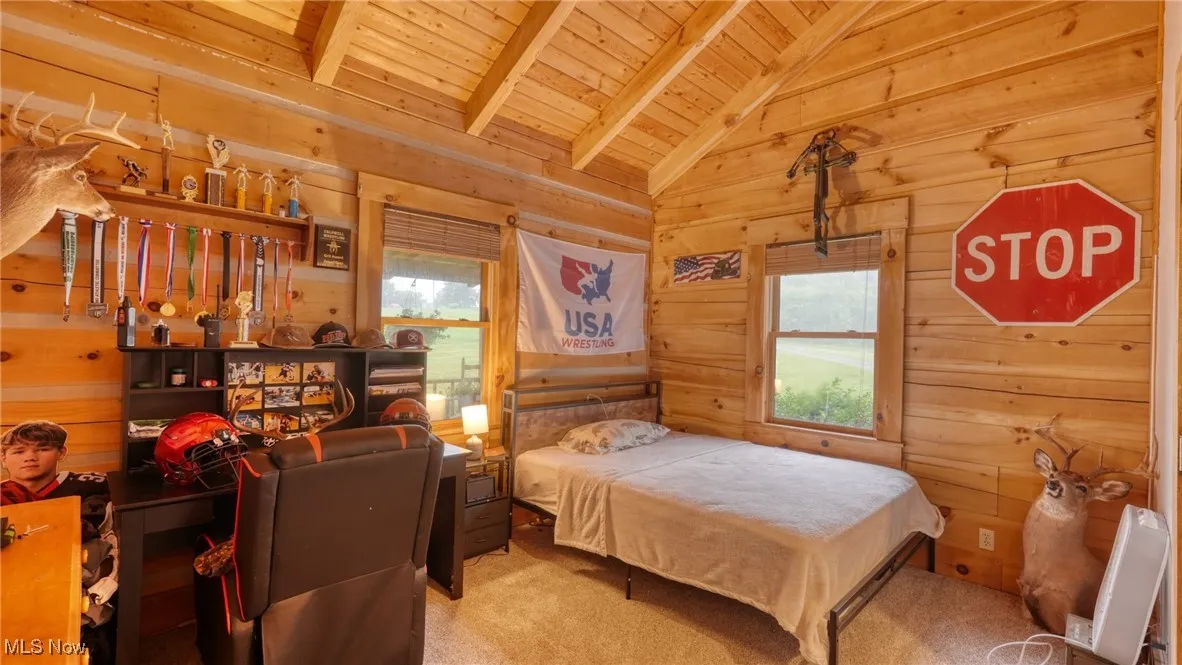 Bedroom with wood ceiling, wood walls, and carpet