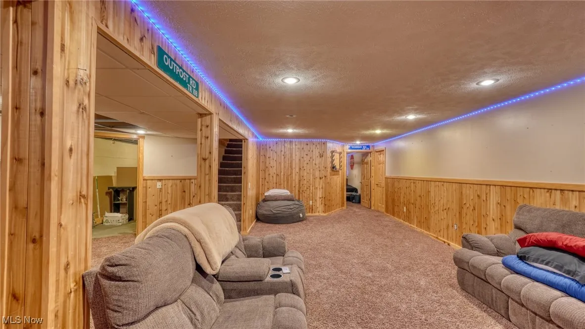 Carpeted home theater room featuring a wainscoted wall, wood walls, a textured ceiling, and recessed lighting