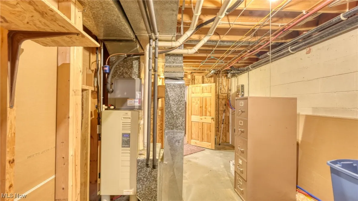 Unfinished basement featuring concrete block wall and heating unit