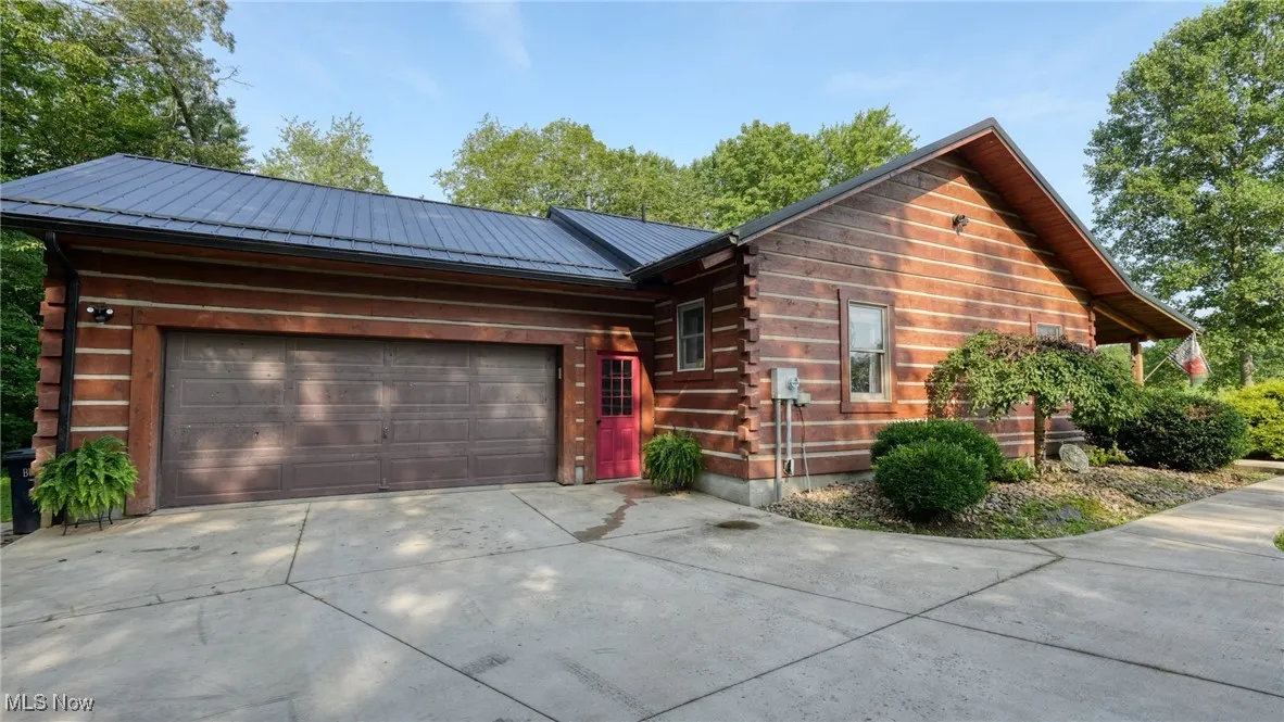 Log home with concrete driveway, log exterior, a garage, and a metal roof
