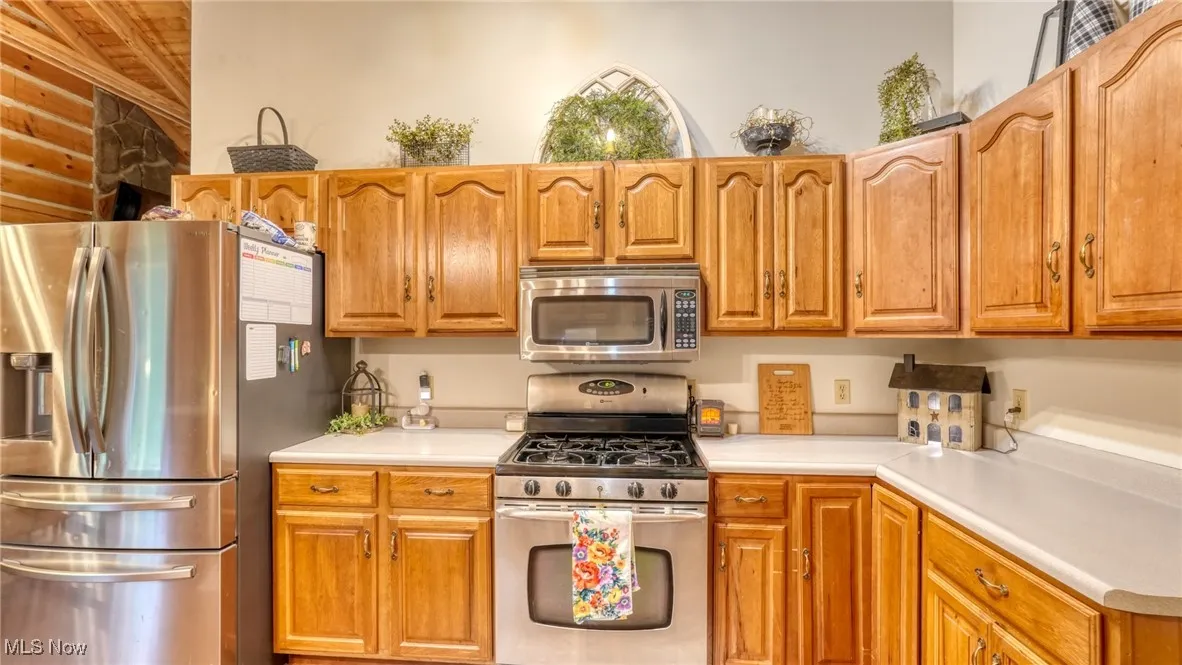 Kitchen featuring stainless steel appliances, light countertops, wood ceiling, and brown cabinets