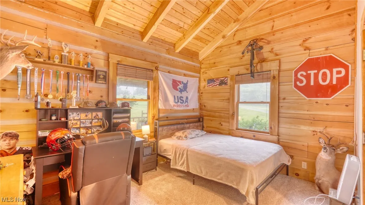 Bedroom featuring wooden ceiling, wood walls, and carpet floors