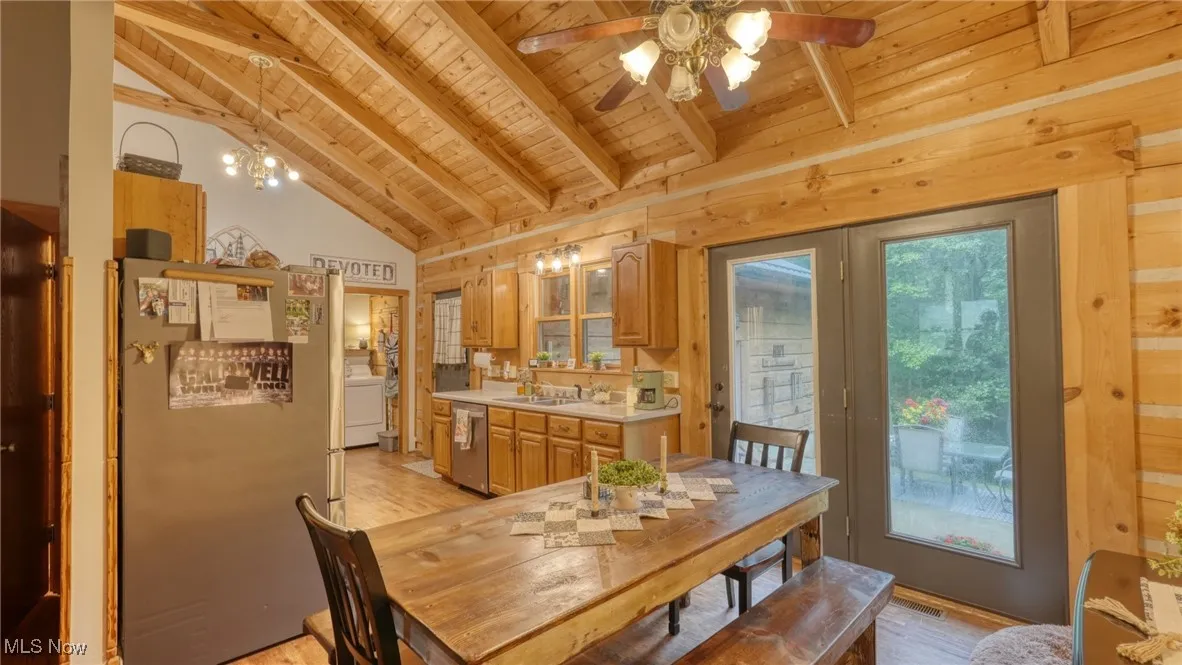 Dining space featuring wooden ceiling, a ceiling fan, light wood-style floors, washer / clothes dryer, and wooden walls