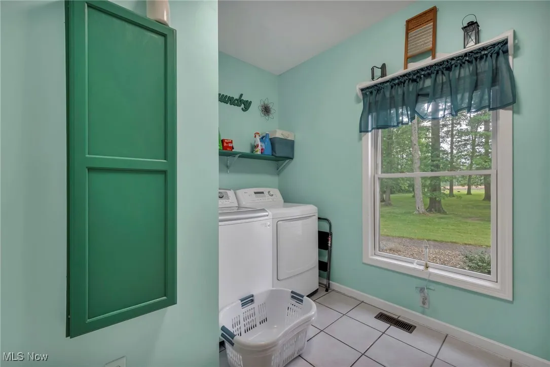 Laundry area featuring washing machine and dryer and light tile patterned floors