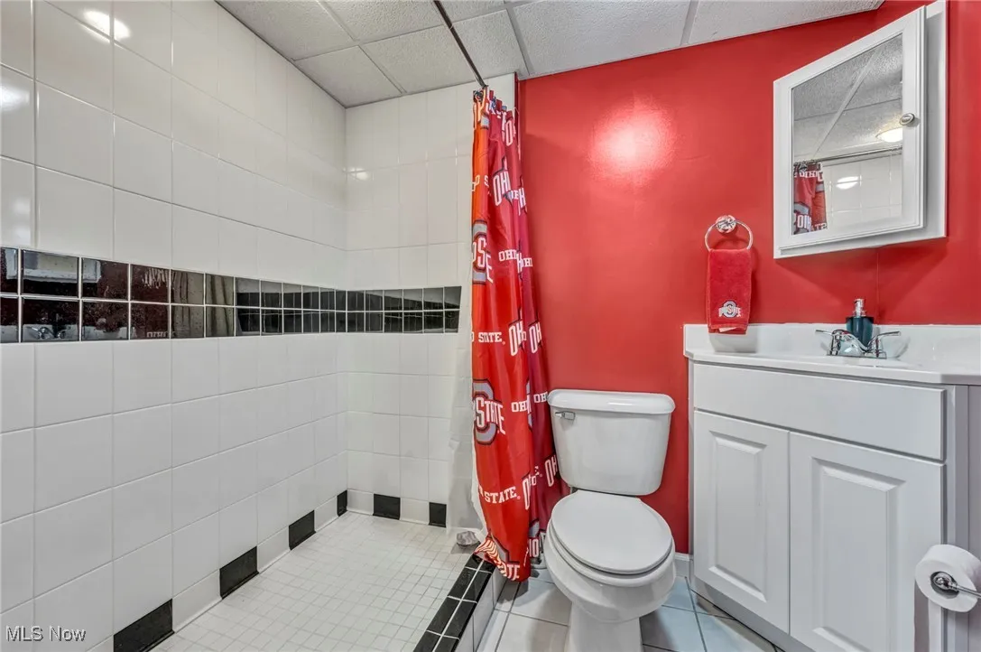 Full bath with vanity, a drop ceiling, tiled shower, and tile patterned floors