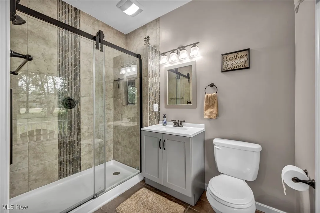 Full bathroom with vanity, a stall shower, and tile patterned floors