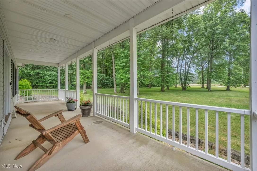Porch featuring a yard and view of wooded area