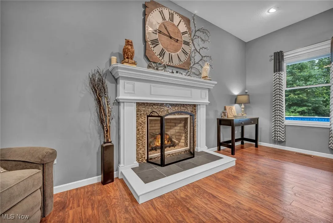 Detailed view of wood finished floors, a premium fireplace, and recessed lighting