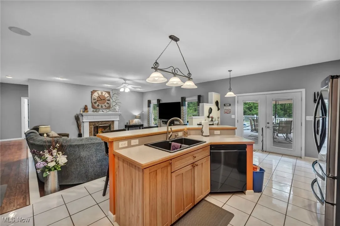 Kitchen with open floor plan, ceiling fan, freestanding refrigerator, a lit fireplace, and dishwasher