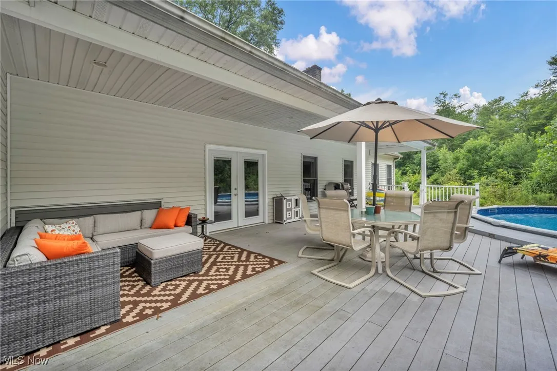 Wooden deck with french doors, an outdoor pool, outdoor dining area, and outdoor lounge area