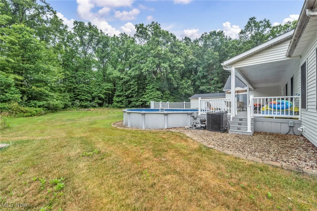 View of green lawn featuring an outdoor pool and a wooden deck