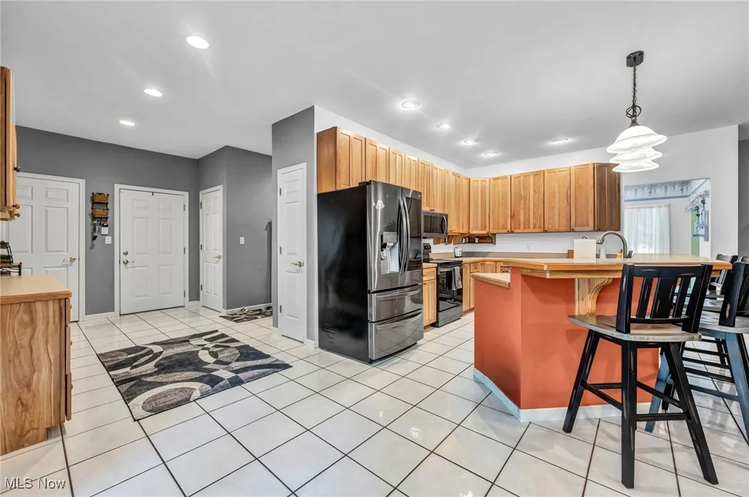 Kitchen featuring appliances with stainless steel finishes, light countertops, a kitchen breakfast bar, recessed lighting, and pendant lighting