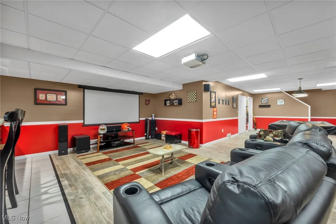 Cinema featuring a drop ceiling and a wainscoted wall