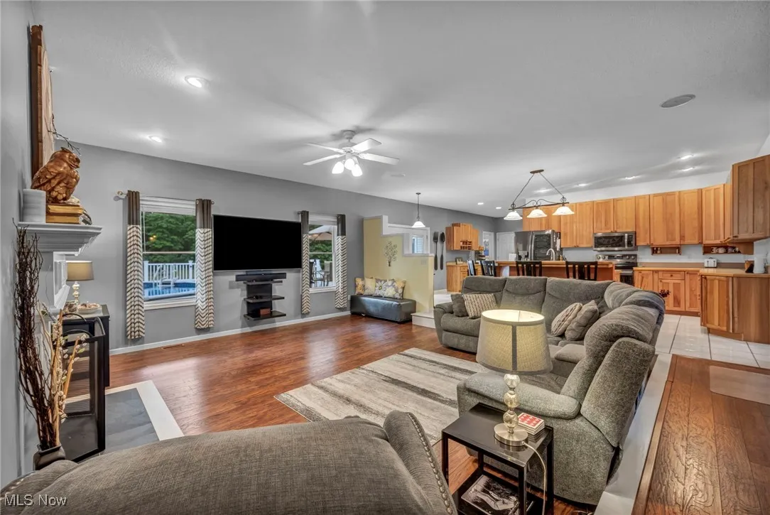 Living room with a fireplace, light wood finished floors, ceiling fan, and recessed lighting