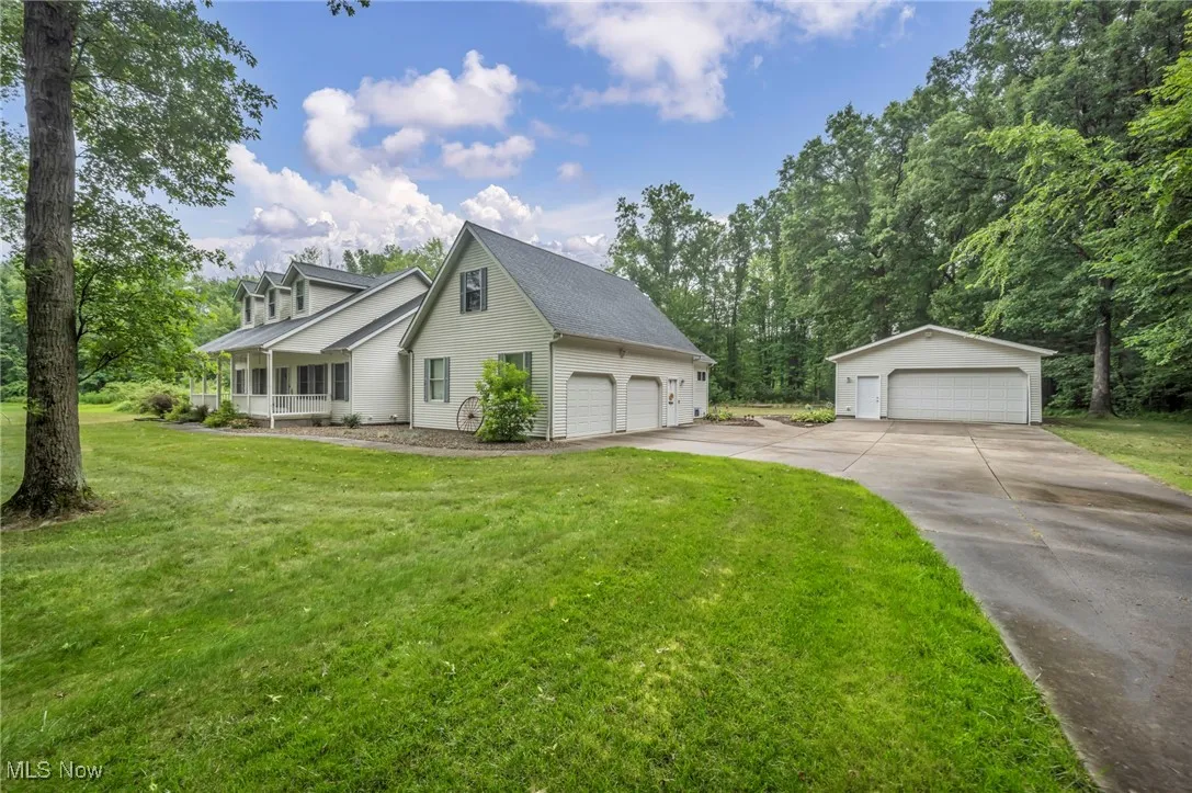 View of front of property with a detached garage, a front lawn, a shingled roof, and an outbuilding