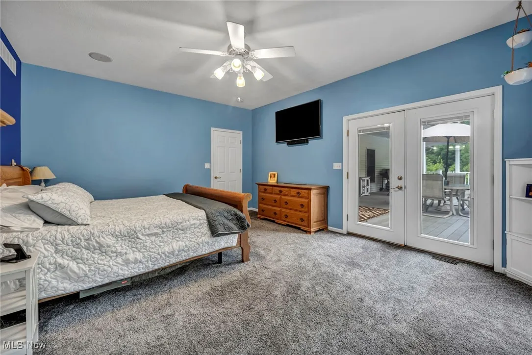 Carpeted bedroom with french doors, access to outside, and ceiling fan