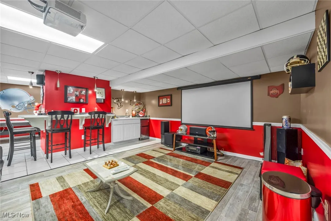 Cinema room with a drop ceiling, bar area, and wood finished floors
